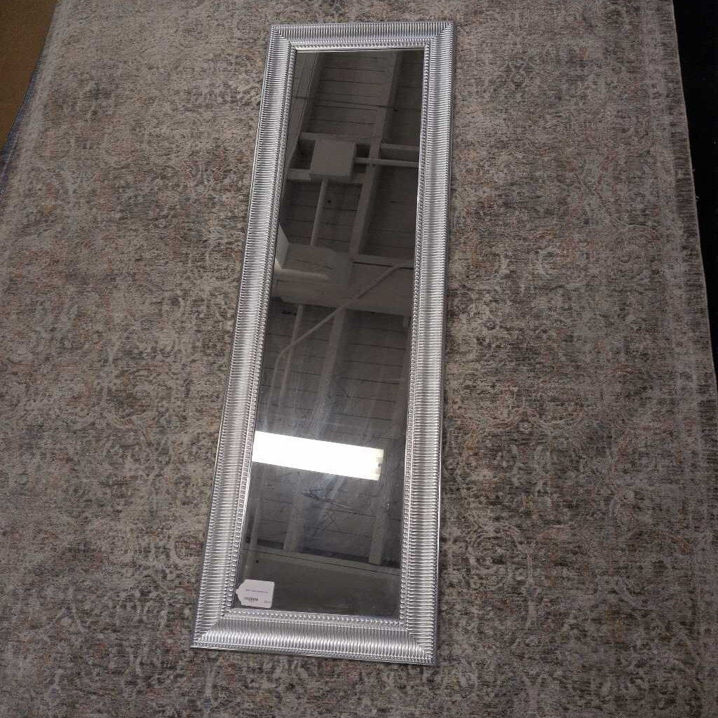 Silver framed mirror on a textured surface