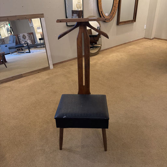 Black stool with wooden base in a room with mirrors on the wall.