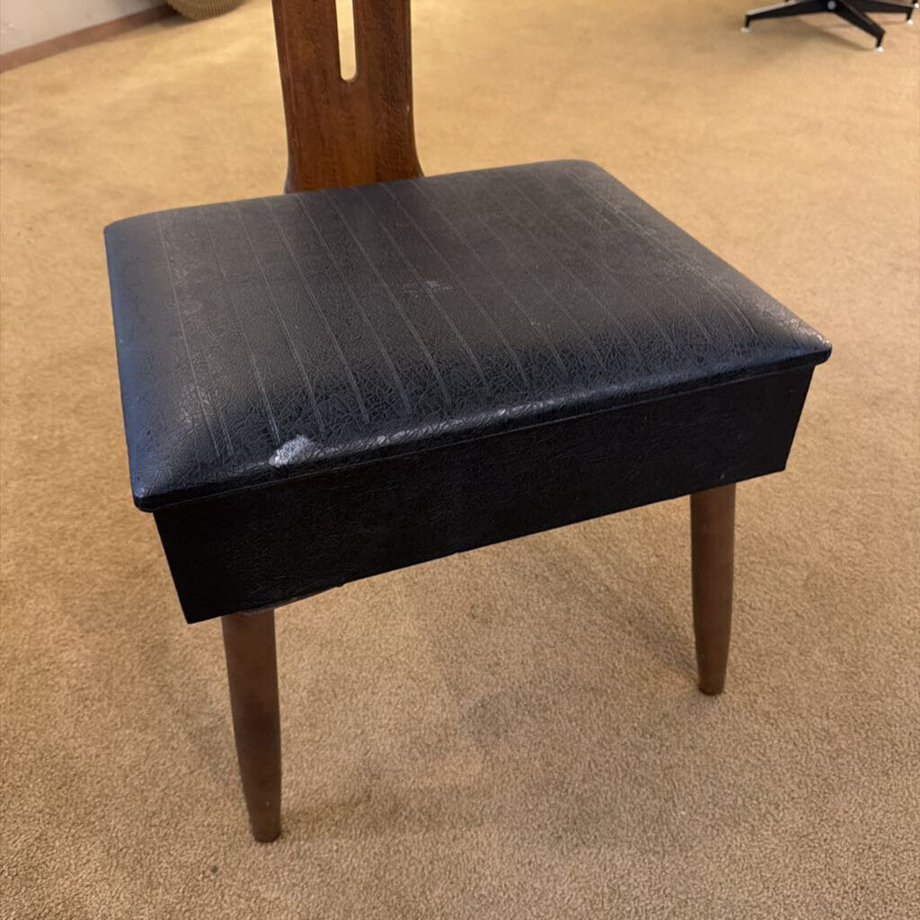 Black stool with wooden legs on a beige carpeted floor