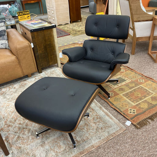 Black leather chair and ottoman on a carpeted floor with furniture and decor in the background.