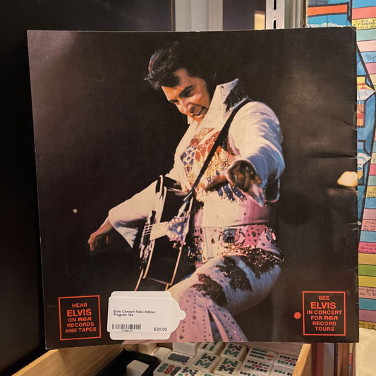 Vinyl record cover featuring an image of a musician in a colorful outfit with text on a shelf.