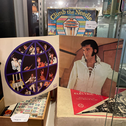 Collection of vinyl records and album covers with a focus on a record featuring a circular design and a portrait of a person.
