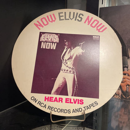 Promotional disc for Elvis Presley with 'Now Elvis Now' text and a black and white photo of Elvis.
