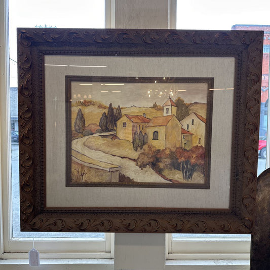 Framed painting of a village scene with a decorative brown frame.