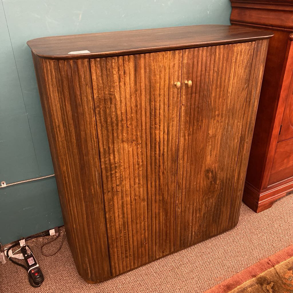 Wooden cabinet against a green wall with a carpeted floor.