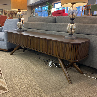 Wooden console table in a living room with gray sofas and lamps.
