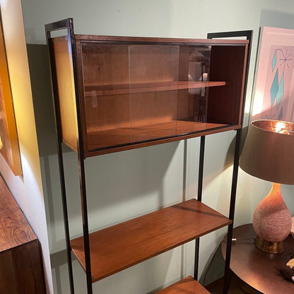 This mid-century modern (MCM) bookshelf features a balanced combination of open display and protected storage. The unit features a minimalist black metal frame that creates a tall, slender silhouette.