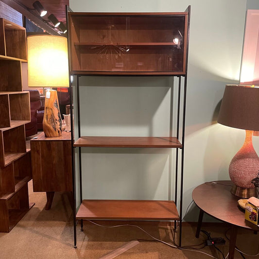 This mid-century modern (MCM) bookshelf features a balanced combination of open display and protected storage. The unit features a minimalist black metal frame that creates a tall, slender silhouette.