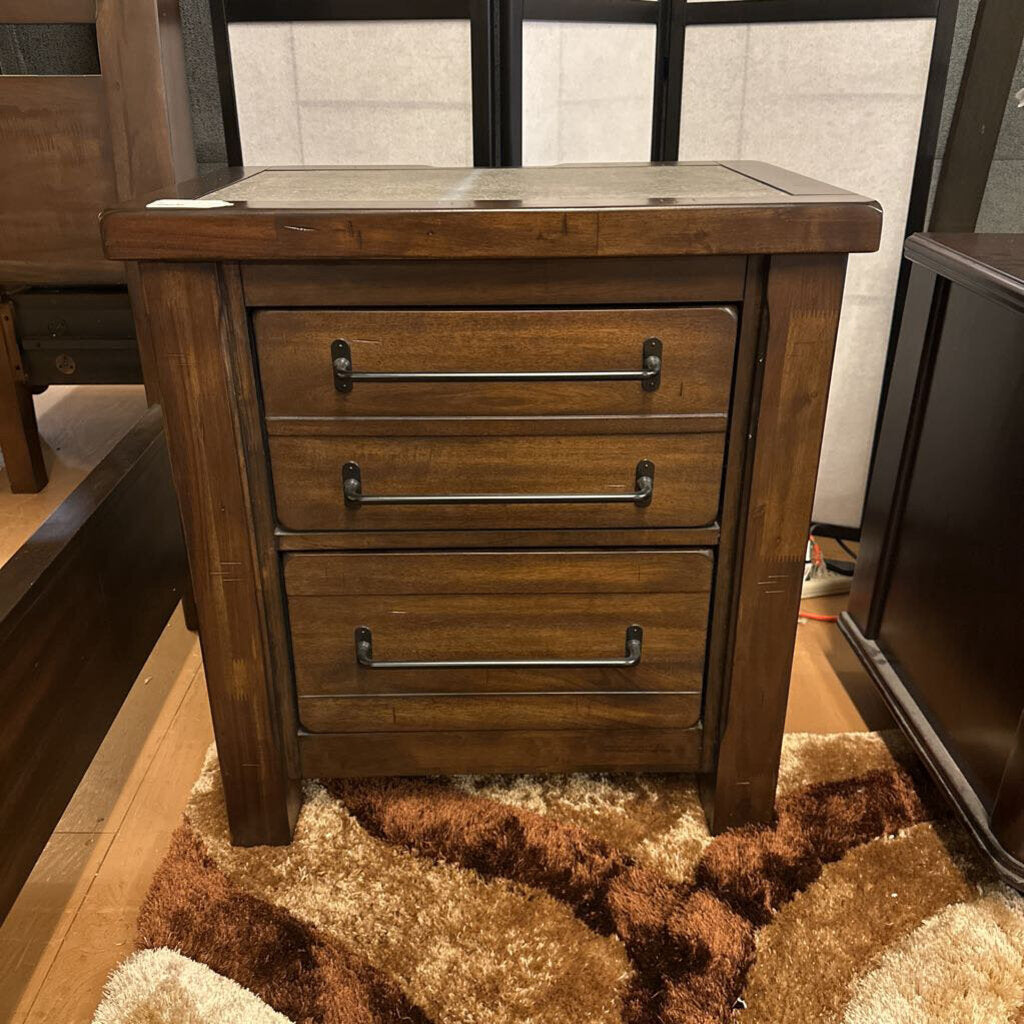 Wooden nightstand with three drawers on a brown rug.