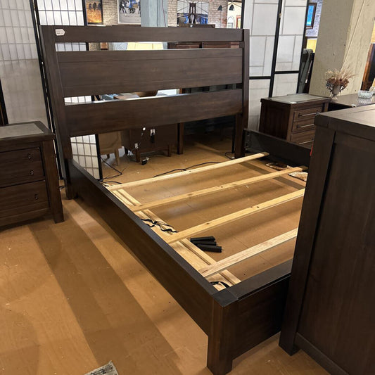 Wooden bed frame without a mattress on a wooden floor.