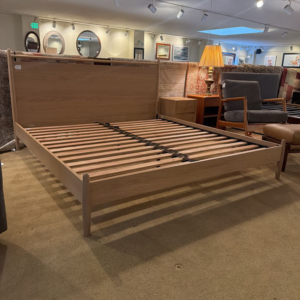 Wooden bed frame in a showroom setting with furniture and decor.