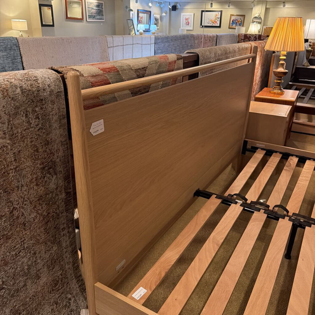 Wooden bed frame with mattress in a showroom setting