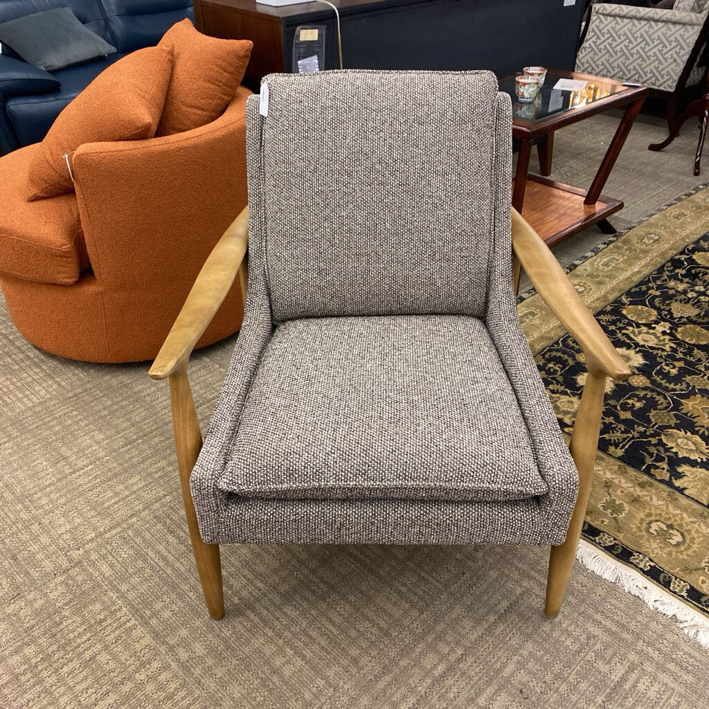 Gray upholstered chair with wooden arms in a room with orange sofa and patterned rug.