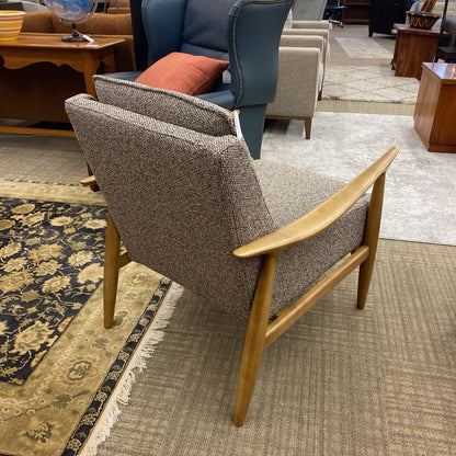 Chair with wooden armrests and backrest in a room with patterned rugs and furniture.