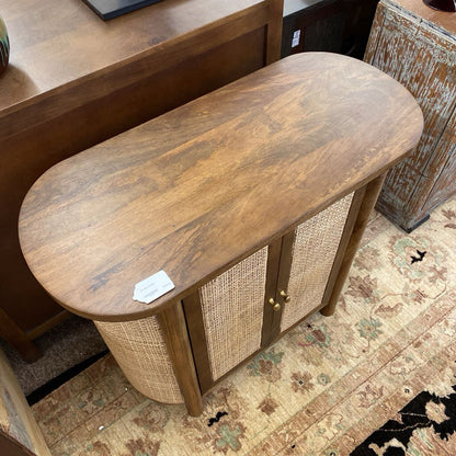 Wooden console table with wicker side against a patterned rug