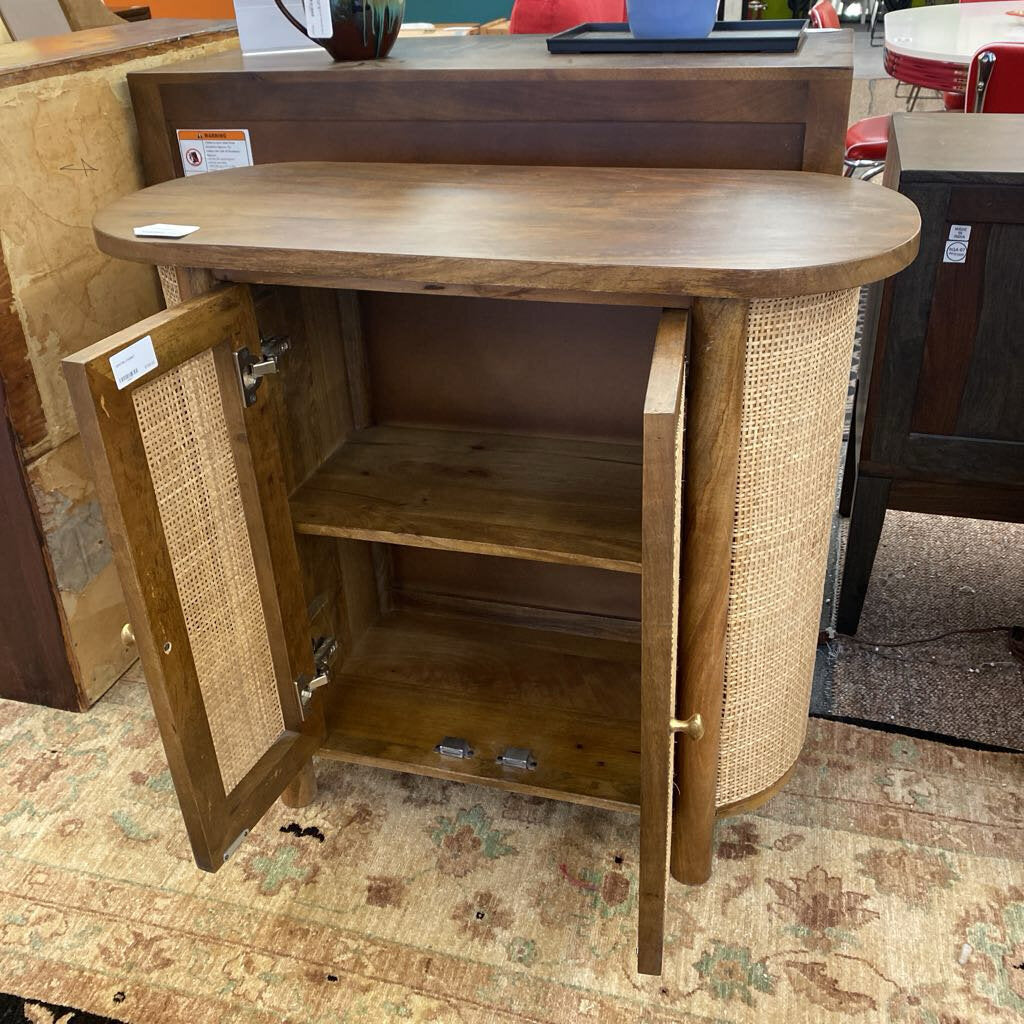 Wooden side table with wicker doors in a store setting
