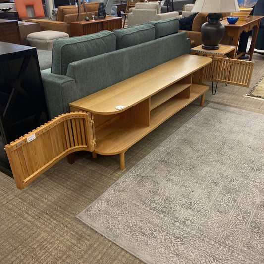 Living room with a green sofa, wooden TV stand, and patterned rug.