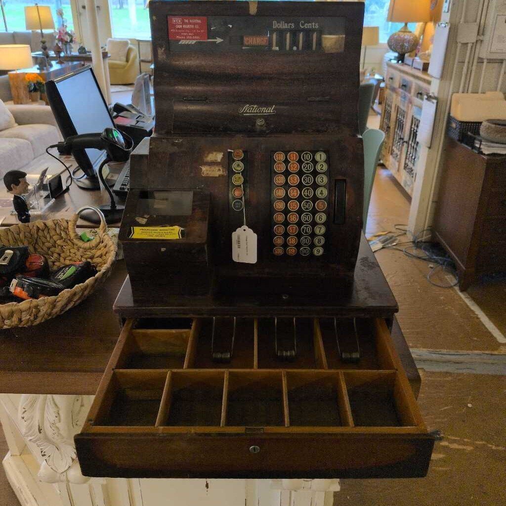 Vintage cash register on a table in a room with furniture and decor.
