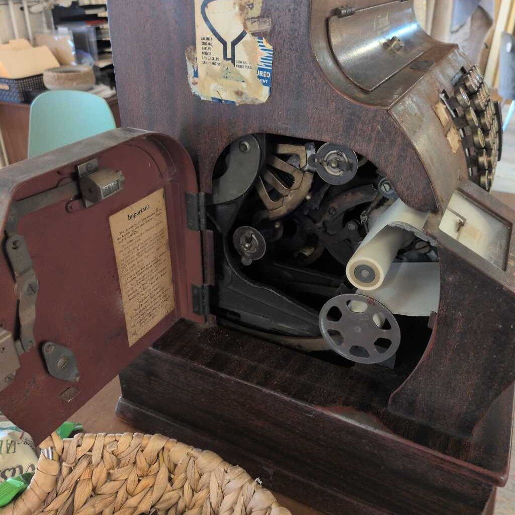Vintage wooden machine with open lid showing mechanical components, surrounded by various items.