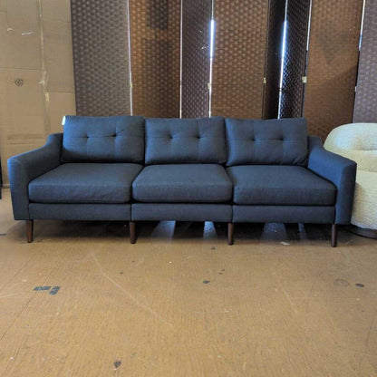 Gray sofa in a room with a textured wall and cardboard floor