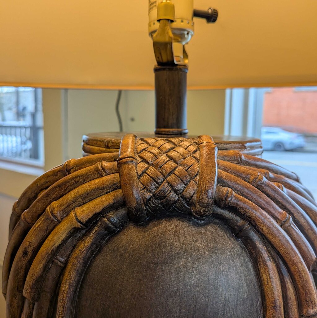 Close-up of a lamp with woven design and yellow shade.
