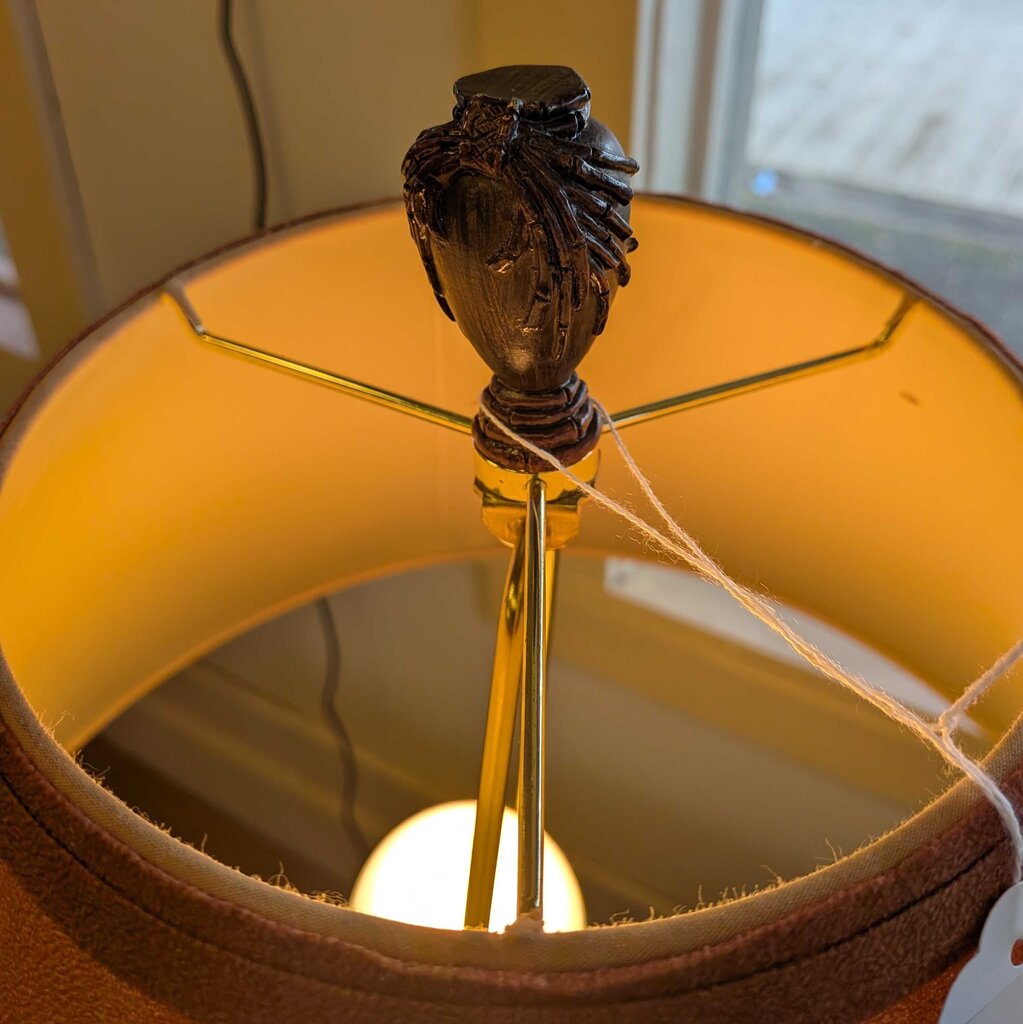 Close-up of a lamp with a decorative base and yellow shade.