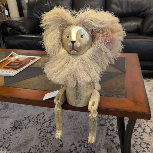 Decorative lion figurine on a wooden table with a black leather couch in the background.
