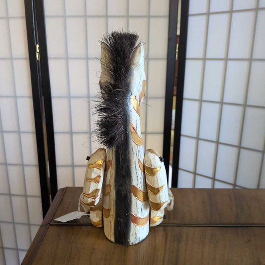 Decorative brush with gold and white patterns on a wooden surface