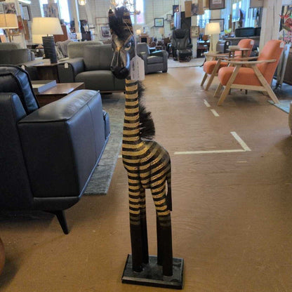 Decorative zebra statue in a furniture store with chairs and tables in the background.