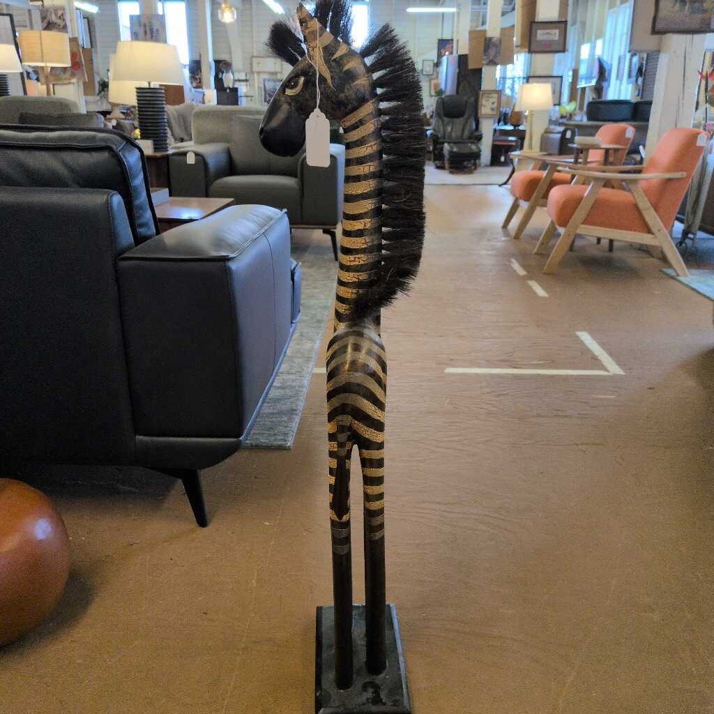 Wooden zebra statue in a furniture store with chairs and tables in the background