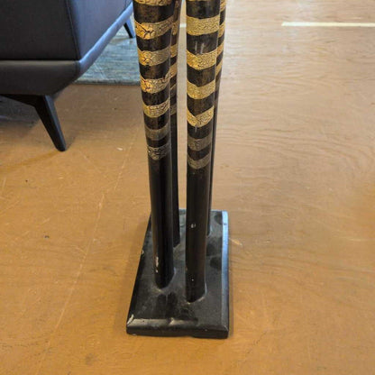 Decorative black and gold pole on a wooden floor