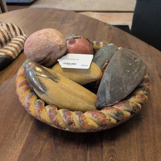 Decorative stone bowl with stones and a fish on a wooden surface