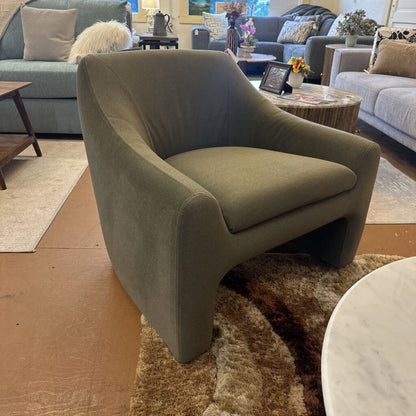 Green armchair in a living room setting with other furniture and decor.