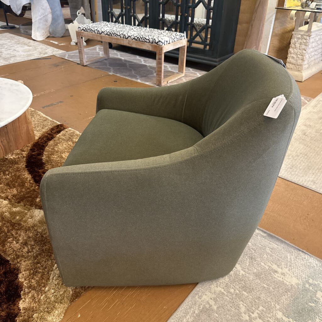 Green armchair in a showroom setting with a tag on it.