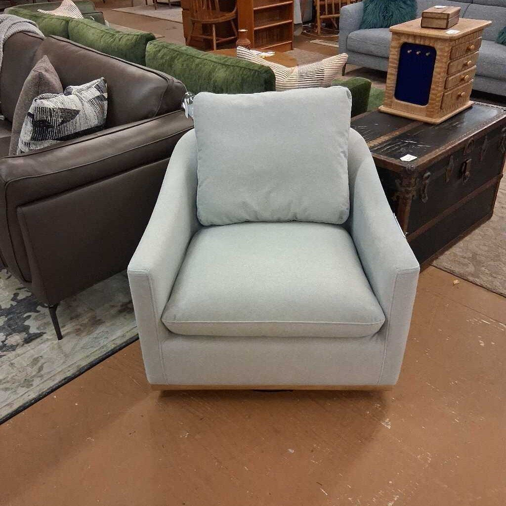 Light blue armchair in a living room setting with a brown sofa and wooden coffee table.