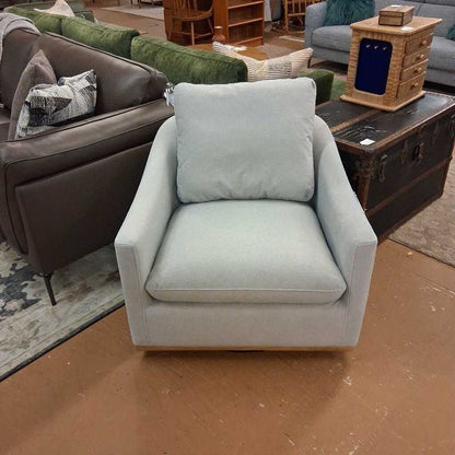 Light blue armchair in a living room setting with a brown sofa and wooden coffee table.