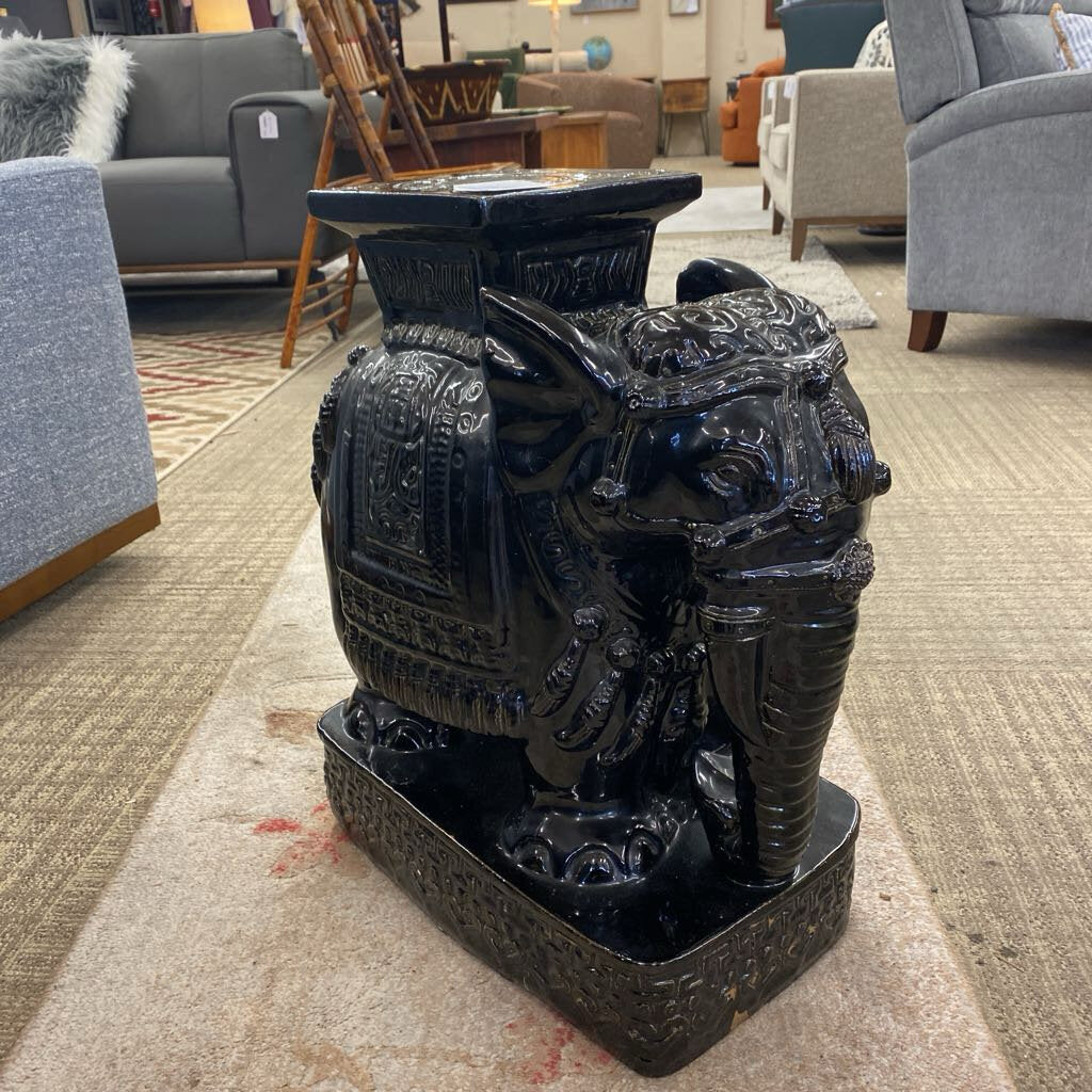 Decorative black urn with intricate designs on a carpeted floor.