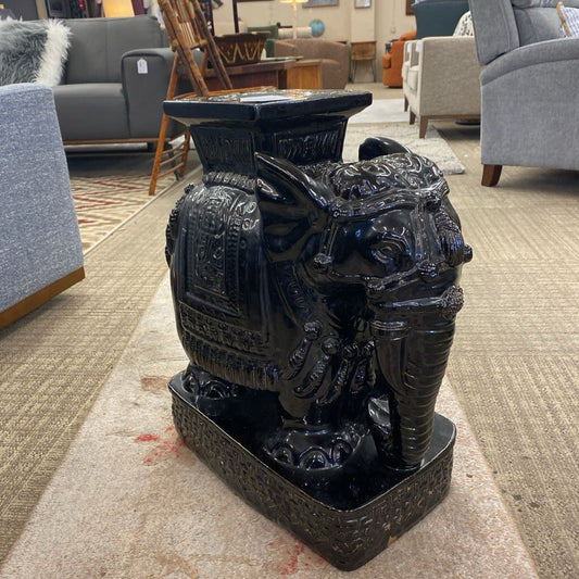 Decorative black urn with intricate designs on a carpeted floor.