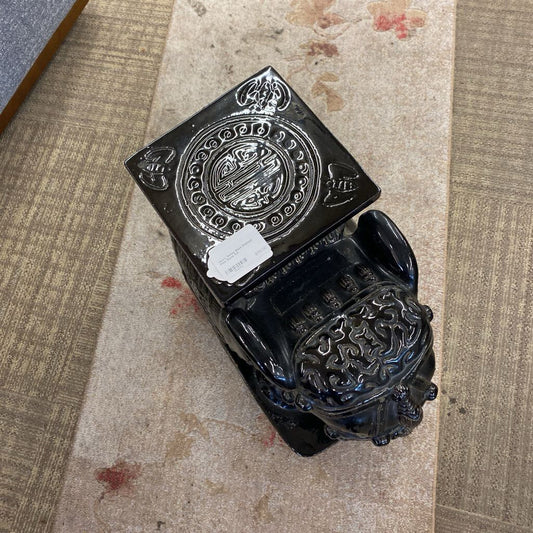Decorative black metal box with intricate designs on a textured surface