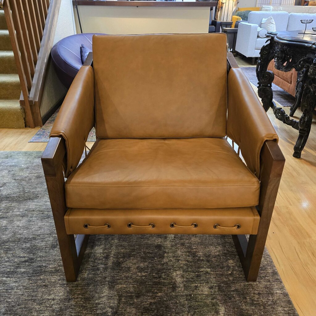 Brown leather armchair in a room with wooden floor and staircase