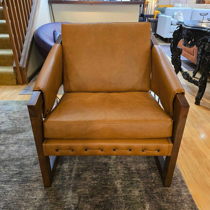 Brown leather armchair in a room with wooden floor and staircase