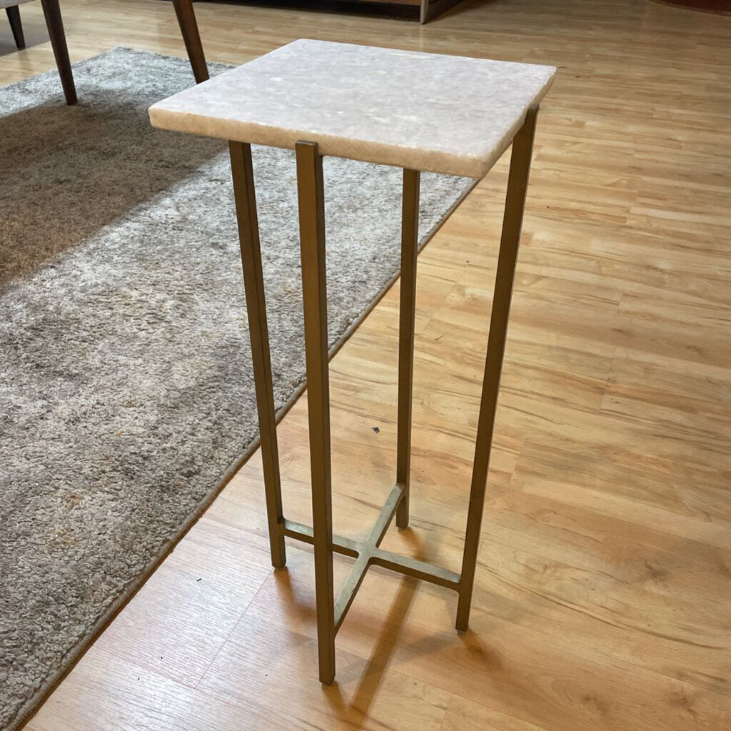 Small square table with marble top and gold legs on a wooden floor
