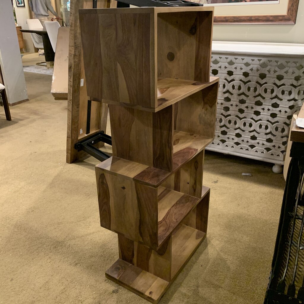 Wooden bookshelf in a store setting with other furniture items.
