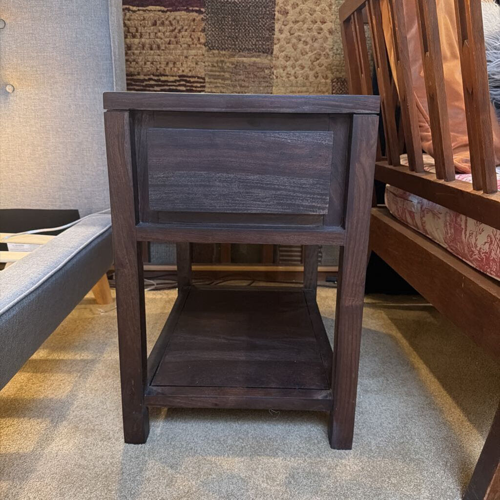 Wooden side table in a room with furniture and a patterned wall.