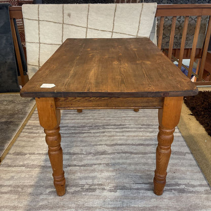 a rustic lightly used solid wood table on a striped rug