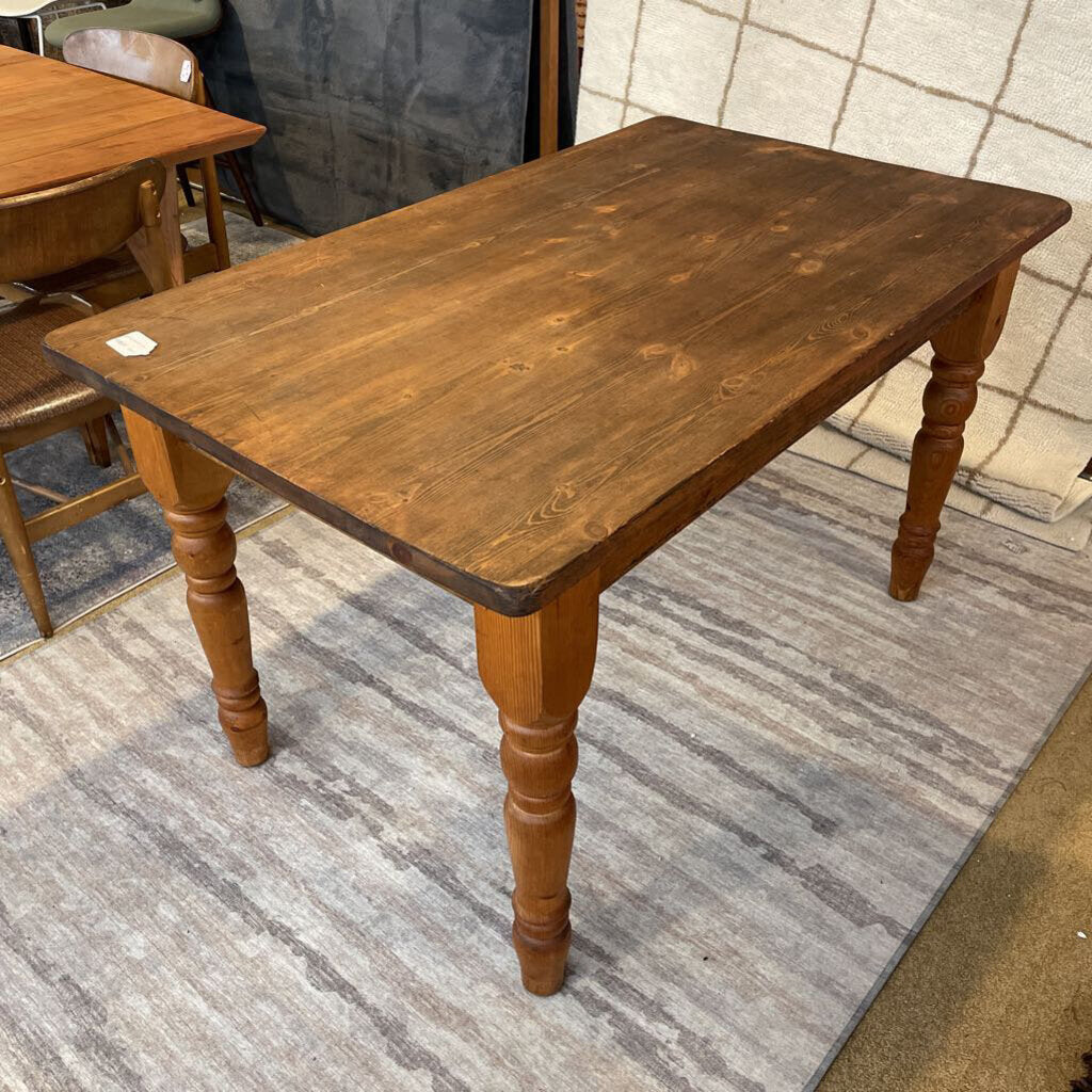 a rustic lightly used solid wood table on a striped rug
