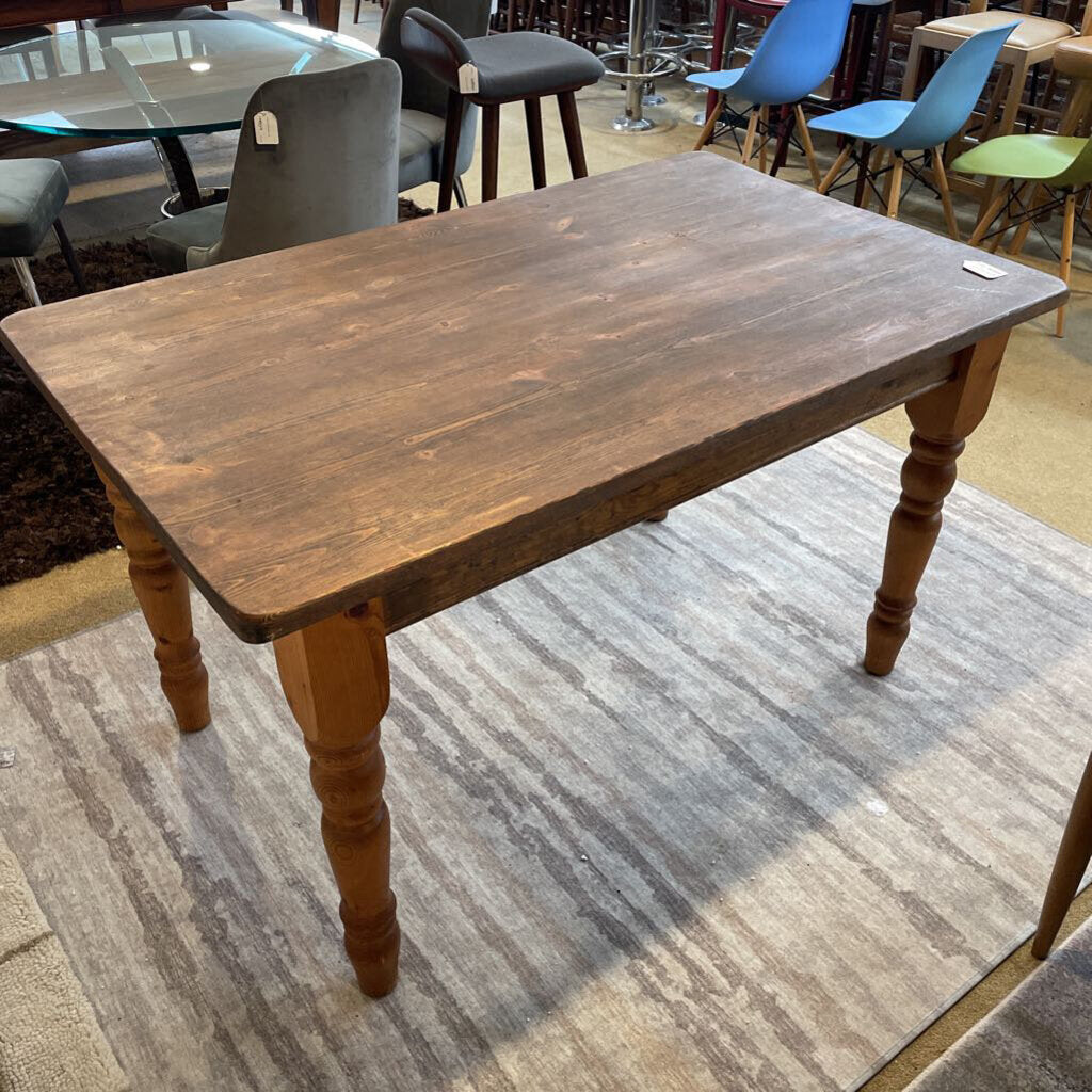 a rustic lightly used solid wood table on a striped rug