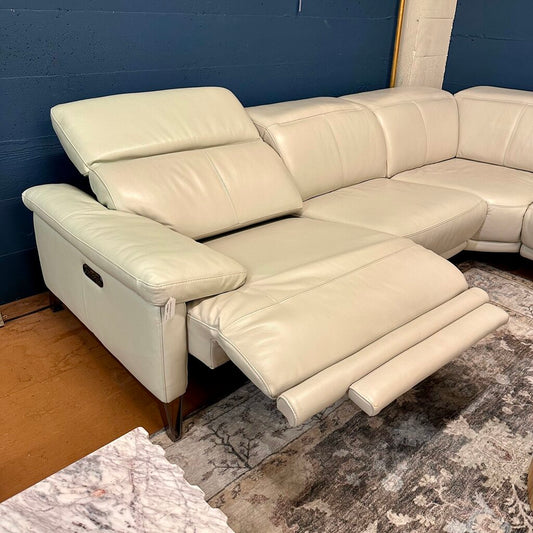 Beige sectional sofa with reclining feature on a patterned rug against a blue wall.