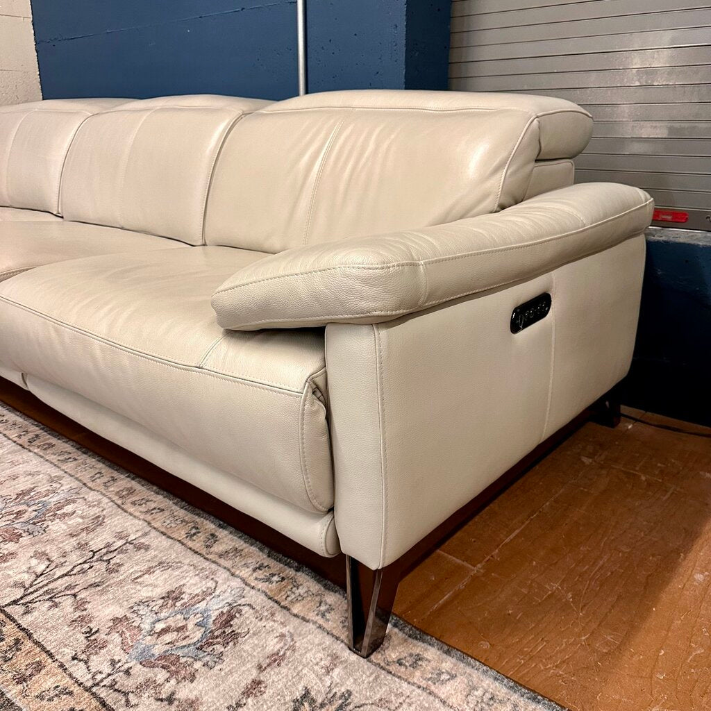 Beige leather sofa in a room with a patterned rug and wooden floor.