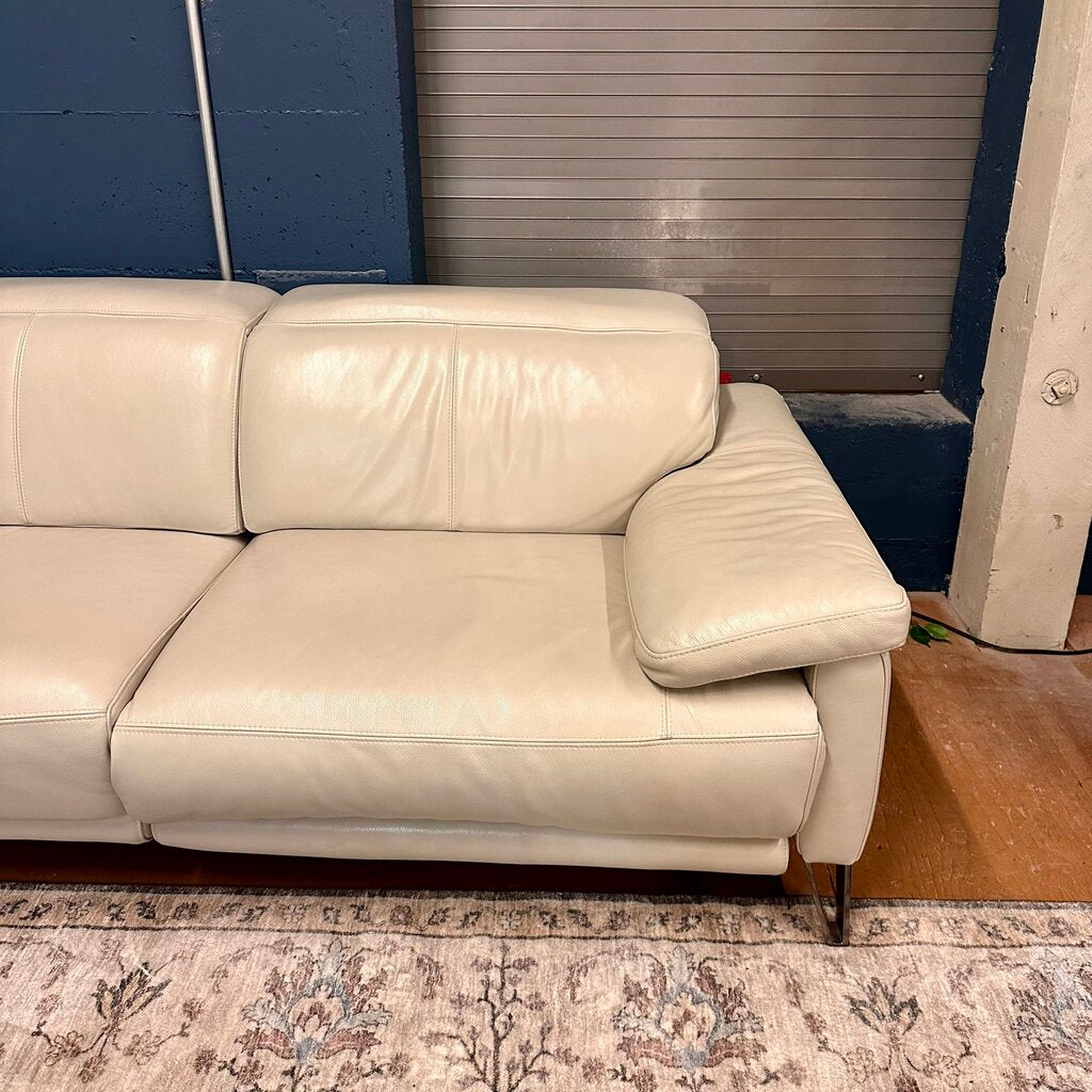 White leather sectional sofa in a room with a blue wall and patterned rug.